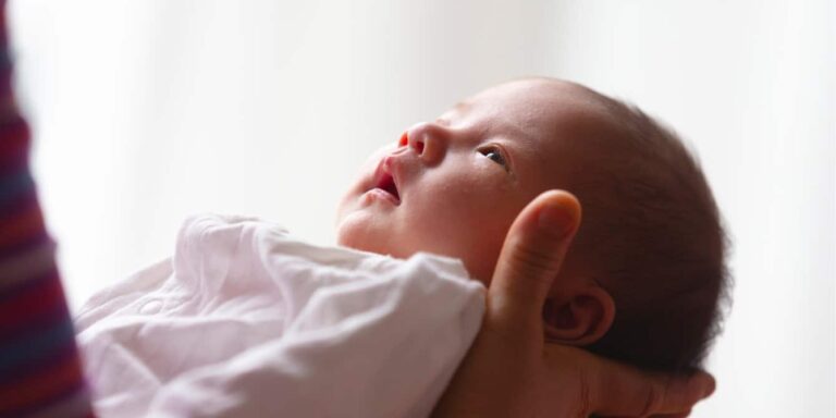 close up of parent holding newborn baby