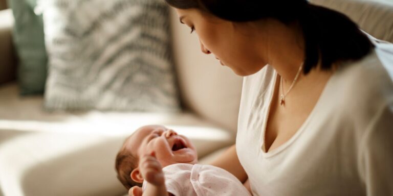 mom holding infant at home pathologizing motherhood