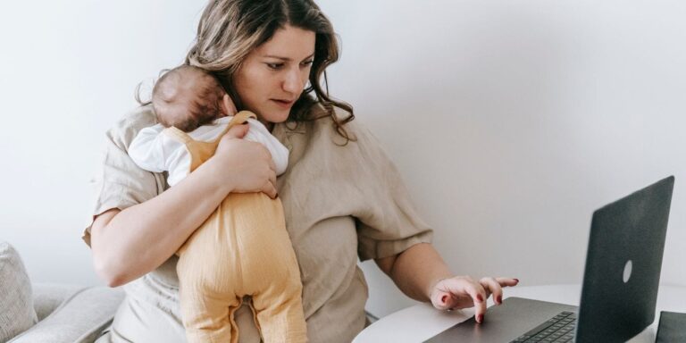 Mom holding baby while working rising childcare costs